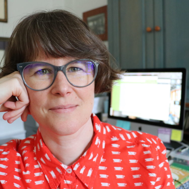 Headshot of a lesbian pictured in front of a desk with a computer monitor.