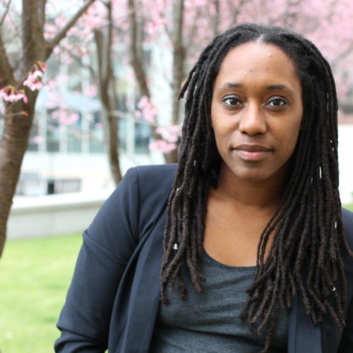 Headshot of a lesbian outside with a blooming tree in the background.