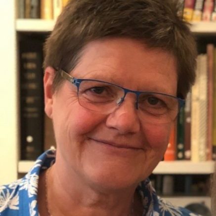 Headshot of a lesbian in front of a bookshelf.