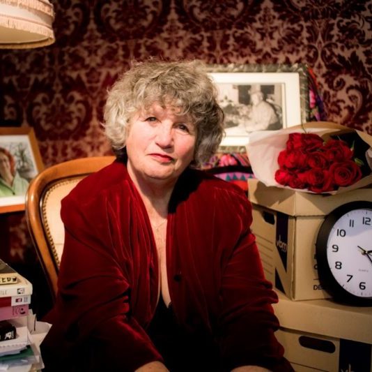 Headshot of a lesbian sitting with a bouquet of roses to her left.