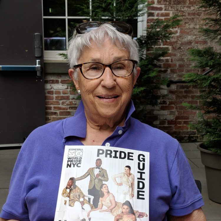 Headshot of a lesbian holding a magazine titled Pride Guide.