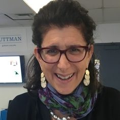 Headshot of a broadly smiling lesbian wearing glasses.