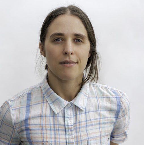 Headshot of a lesbian wearing a plaid shirt.