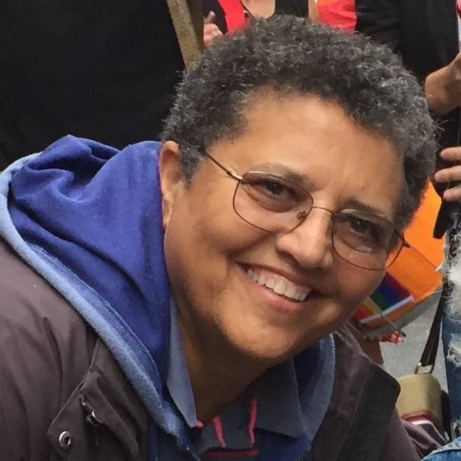 Headshot of a broadly smiling lesbian.