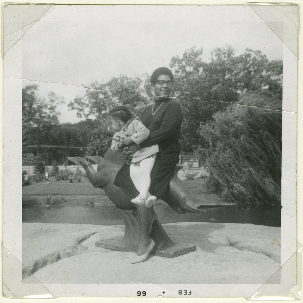 A vintage black-and-white photograph of a Black Lesbian holding a small child.