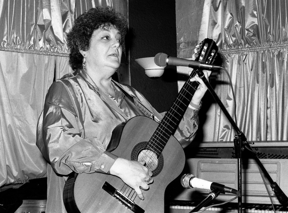 Black and white photo of Madeline Davis playing a guitar.